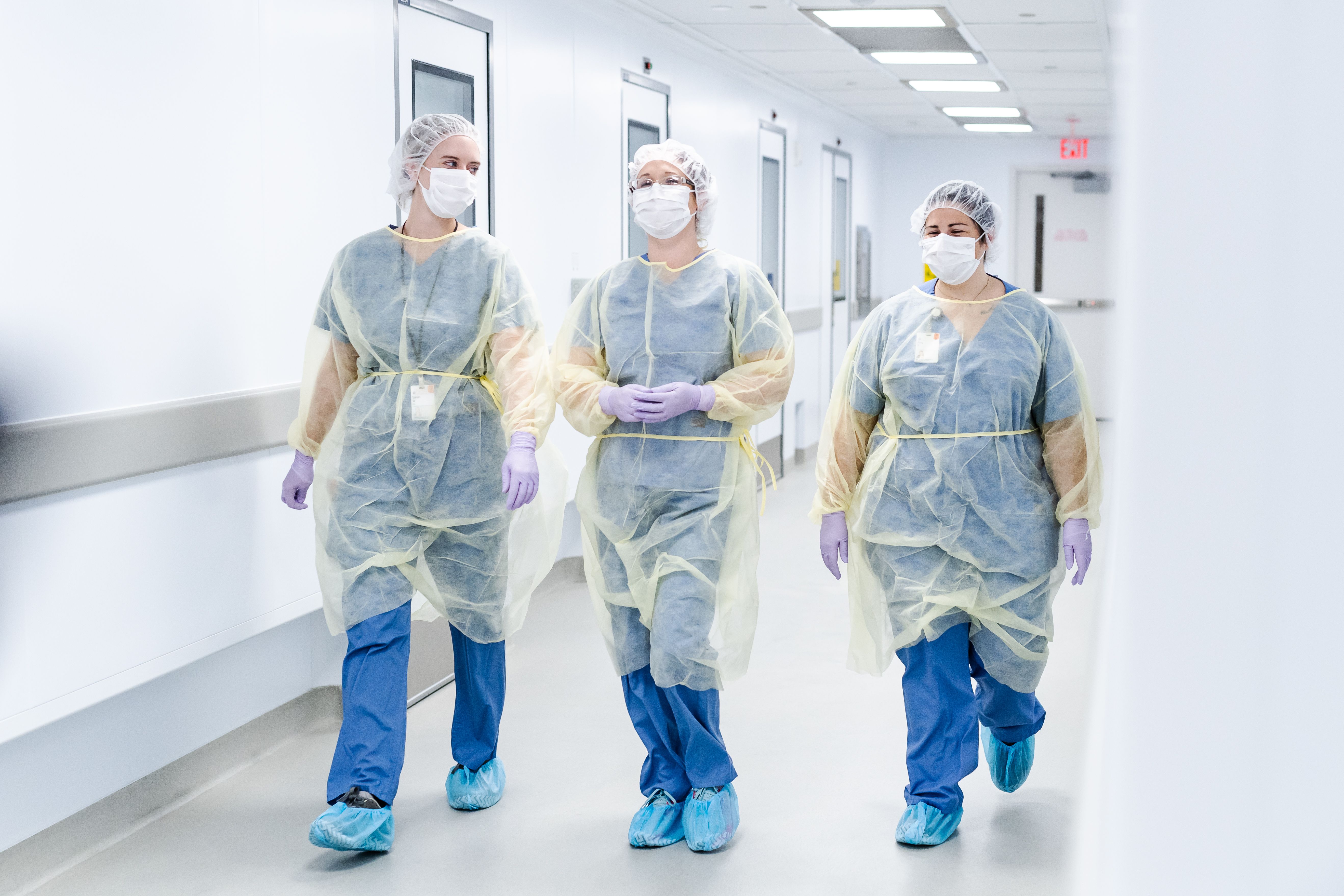 Three healthcare professionals in scrubs and gowns
