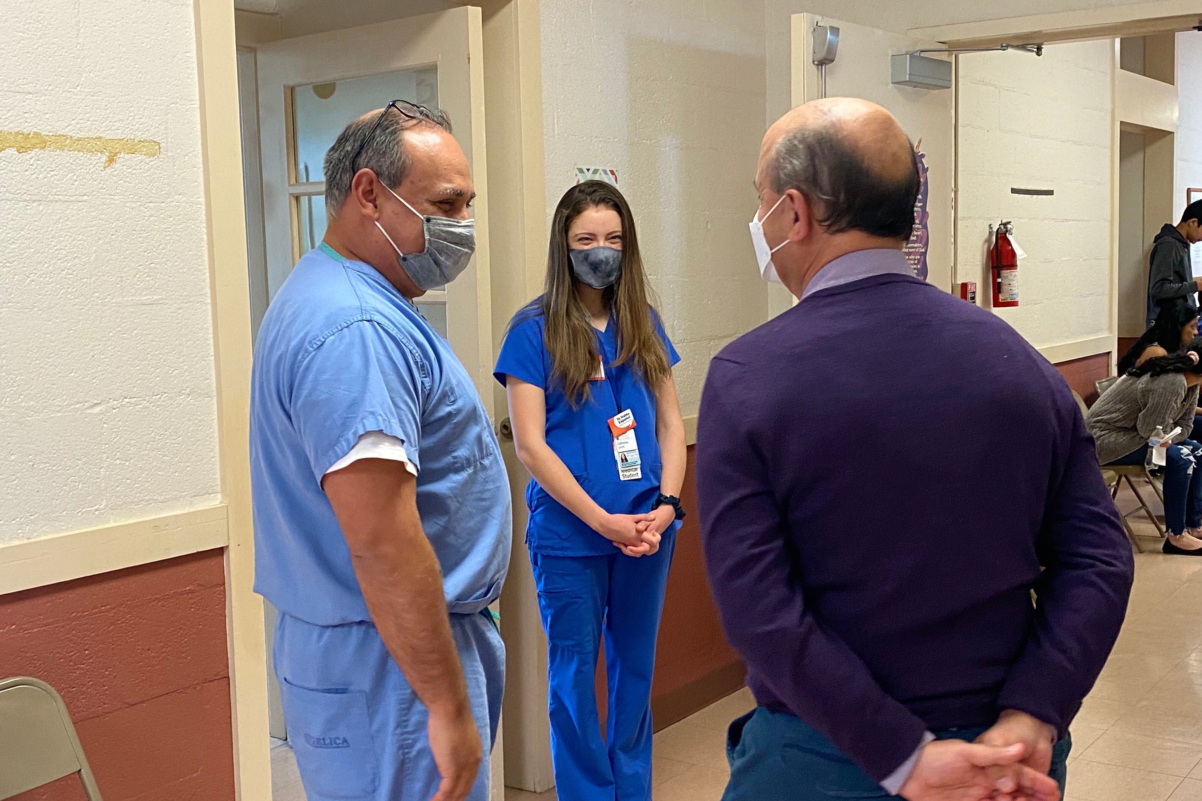 Three medical professionals talking in a hospital hallway